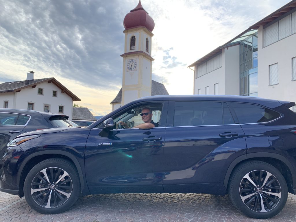 Fabio Orecchini al volante Toyota Highlander Hybrid con campanile Dolomiti San Pietro di Laion